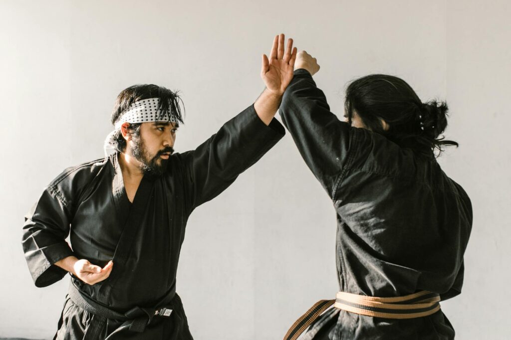 Two martial artists practicing self-defense techniques indoors in a focused session.